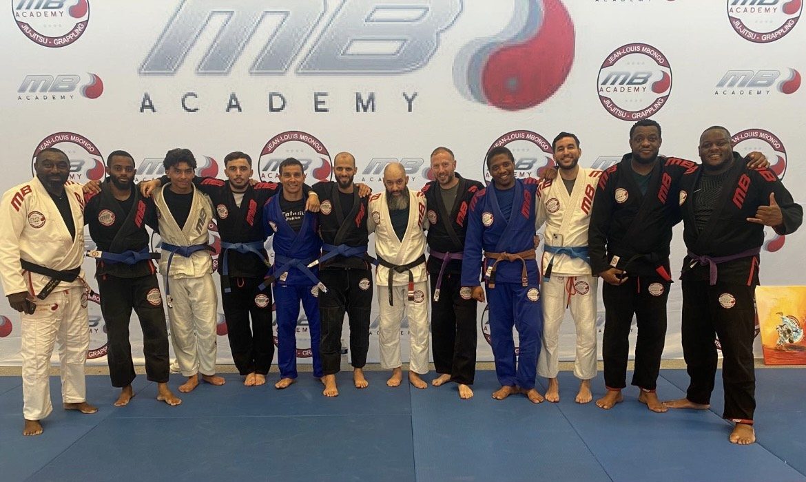Photo de groupe en kimono devant la bannière de l'académie de jiu-jitsu brésilien